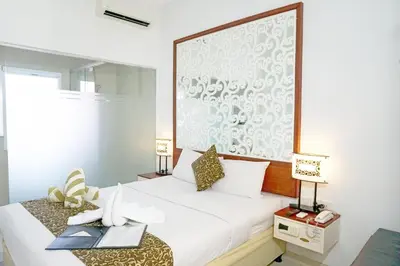 a bedroom with a white bed with a large picture on the wall at Samsara Inn in Legian