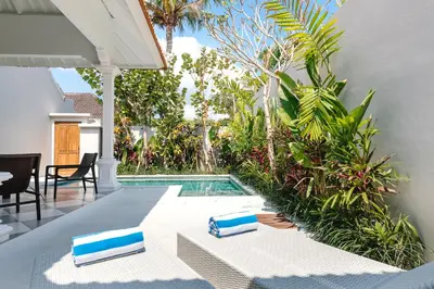 a pool with two lounge chairs next to a house at Villa Luma in Seminyak