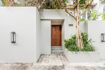 a white house with a wooden door and a tree at Central 1 Bedroom Villa 5 Min walk to Seminyak Beach in Seminyak