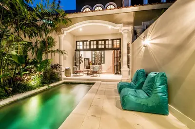 an indoor pool with a green couch next to a house at Central 1 Bedroom Villa 5 Min walk to Seminyak Beach in Seminyak