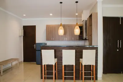 a kitchen with a bar with white chairs and lights at White Lotus Villas Seminyak in Seminyak