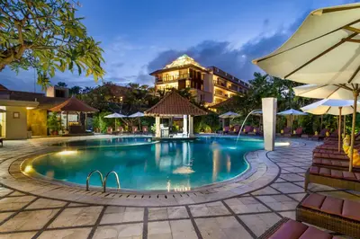 a swimming pool at a resort with a building in the background at Puri Raja Hotel in Legian