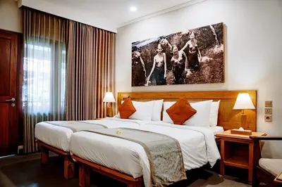 a hotel room with two beds and a painting on the wall at Puri Raja Hotel in Legian