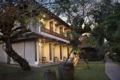 a building with a balcony and tables and trees at Matahari Bungalow in Legian