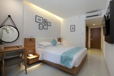 a bedroom with a bed and a desk and a mirror at Matahari Bungalow in Legian