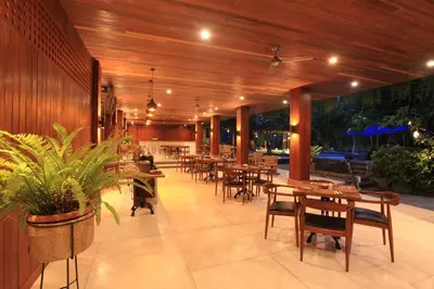 a restaurant with wooden walls and tables and chairs at Matahari Bungalow in Legian
