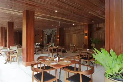 a restaurant with wooden walls and tables and chairs at Matahari Bungalow in Legian