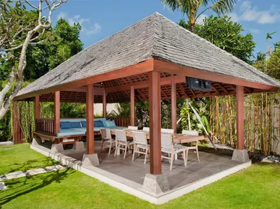 a wooden gazebo with a table and chairs at Villa Joss Seminyak by Nagisa Bali in Seminyak