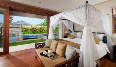 a bedroom with a canopy bed and a couch at Villa Joss Seminyak by Nagisa Bali in Seminyak