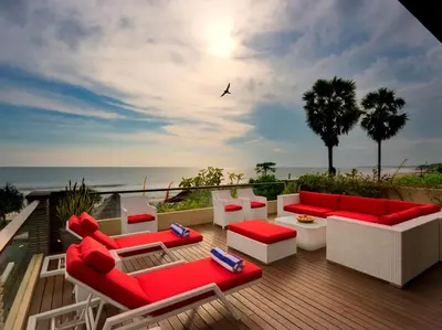 a patio with red and white furniture and the ocean at Villa LeGa in Seminyak