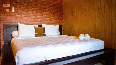 a bedroom with a bed with a brick wall at Leyeh Leyeh Homestay in Canggu