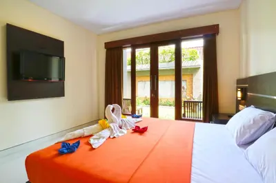 a bedroom with a bed with towels and a flat screen tv at Gempita House Legian Bali in Legian