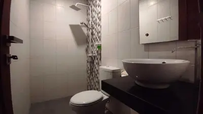 a bathroom with a white toilet and a sink at Gempita House Legian Bali in Legian