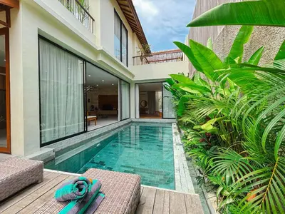 a swimming pool next to a villa with two lounge chairs at NEW 2BR Minica Villa in the heart of Kayu Aya, Oberoi, Seminyak walking distance to Beach, Shops, Restaurants in Seminyak