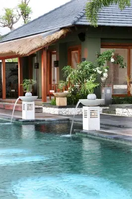 a pool with two fountains in front of a house at Villa Hening Jimbaran in Jimbaran