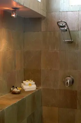 a bathroom with a shower with a stone wall at Villa Hening Jimbaran in Jimbaran