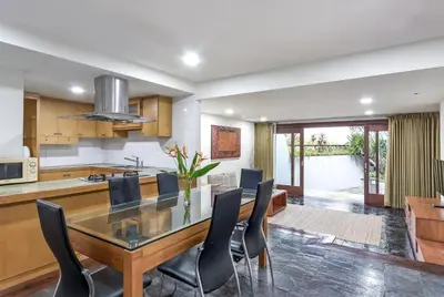 a kitchen and dining room with a glass table and chairs at Villa Hening Jimbaran in Jimbaran