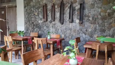 a restaurant with wooden tables and chairs and a stone wall at Uma Karan in Seminyak