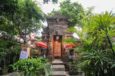a temple in the middle of a garden with trees at Legian Village Hotel - CHSE Certified in Legian