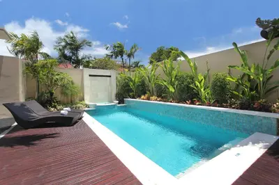 a swimming pool with a chair next to a house at RC Villas and Spa Bali in Seminyak