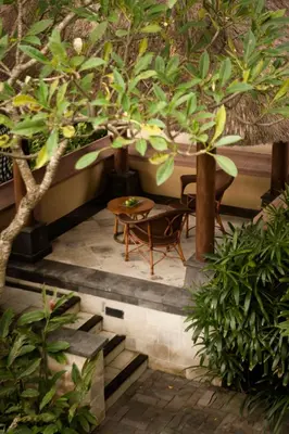 a patio with a table and chairs under a tree at Villas at The Patra Bali Resort and Villas - CHSE Certified in Kuta