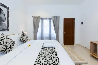 a bedroom with a large bed with black and white pillows at Amerta Seminyak in Seminyak