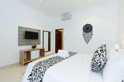 a white bedroom with a bed and a tv at Amerta Seminyak in Seminyak