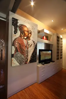 a living room with a tv and a painting on the wall at Sejuk Suites in Legian