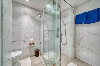a bathroom with a glass shower and a toilet at Sejuk Suites in Legian