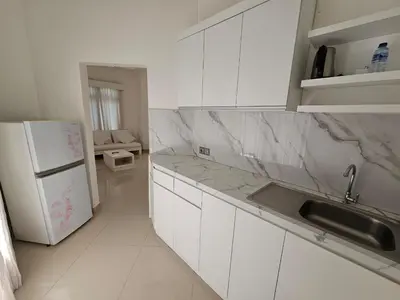 a white kitchen with a sink and a refrigerator at Nipuri Resort and Villas Seminyak by Kamara in Seminyak