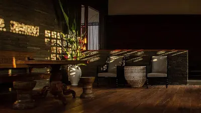 a room with a table and chairs and a brick wall at Villa Indrani in Canggu