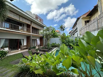 a courtyard of a building with a pool and plants at Balcony Living Apartment in Seminyak