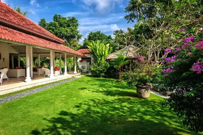 a garden of a house with green grass and flowers at Villa Sipo in Seminyak
