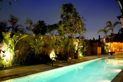 a swimming pool in a backyard at night with lights at Sasa Bali Villas in Seminyak