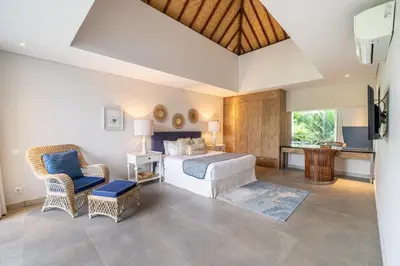 a bedroom with a bed and a chair and a tv at Villa Jekumah 2 in Seminyak