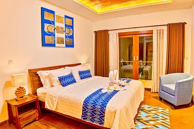 a bedroom with a bed and a blue chair at Villa Caitlyn, Seminyak - Modern 3 Bedroom Villa with Private Pool! in Seminyak