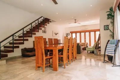 a dining room with a table and chairs and a staircase at Charming Private Villa with Pool in Canggu
