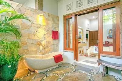 a bathroom with a tub and a stone wall at Villa Ellen in Seminyak