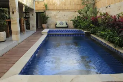 a pool in the middle of a house with blue water at Villa Margaux in Seminyak