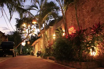 a street at night with palm trees and plants at Villa Margaux in Seminyak