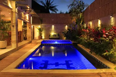a swimming pool in the middle of a garden at night at Villa Margaux in Seminyak