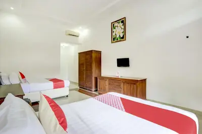 a bedroom with two beds and a tv on the wall at Hotel O Ratu in Denpasar