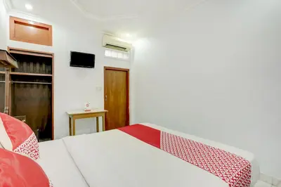 a bedroom with a white bed and a tv at Hotel O Ratu in Denpasar