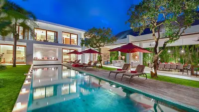 a house with a swimming pool with chairs and umbrellas at Casa Brio in Seminyak