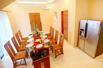 a dining room with a table and a refrigerator at Villa Alessandra Seminyak By Bali Asia Villa in Seminyak