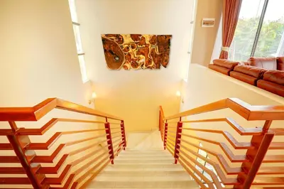a hallway with wooden stairs and a painting on the wall at Villa Alessandra Seminyak By Bali Asia Villa in Seminyak