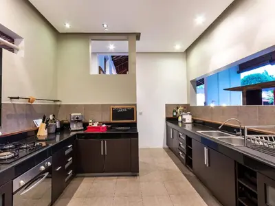 a large kitchen with black counters and a sink at Villa Arte by Villa Finder in Seminyak