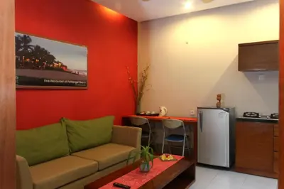 a living room with a couch and a kitchen at The Green Zhurga Suite Seminyak in Kerobokan