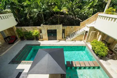 a swimming pool with a black umbrella in a yard at Beach Melati Apartments in Legian