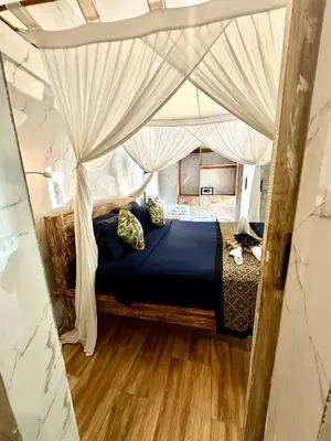 a bedroom with a canopy bed with blue sheets and pillows at Kubu Guest House in Seminyak